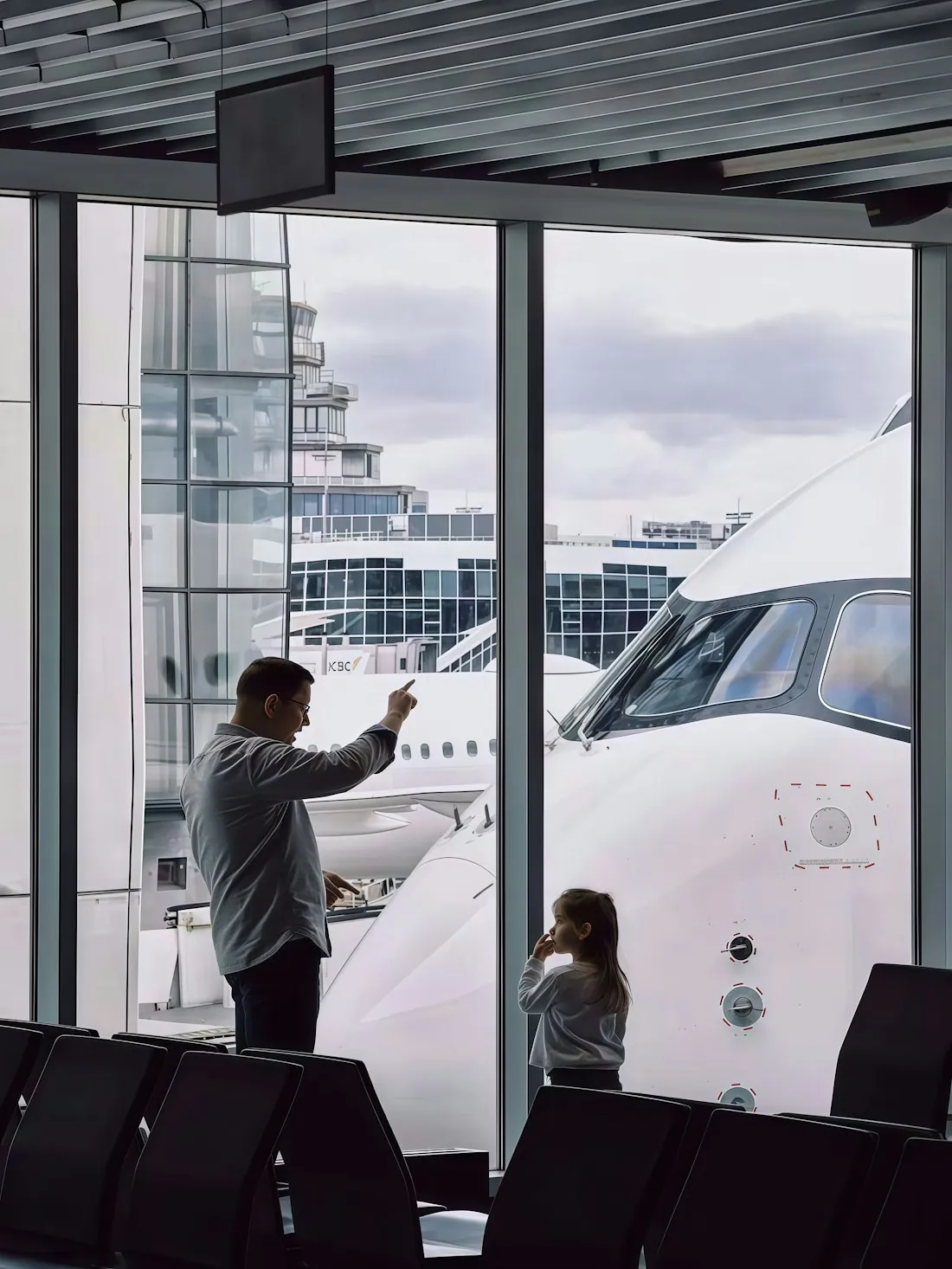 A parent and child pointing at an aircraft parked outside
